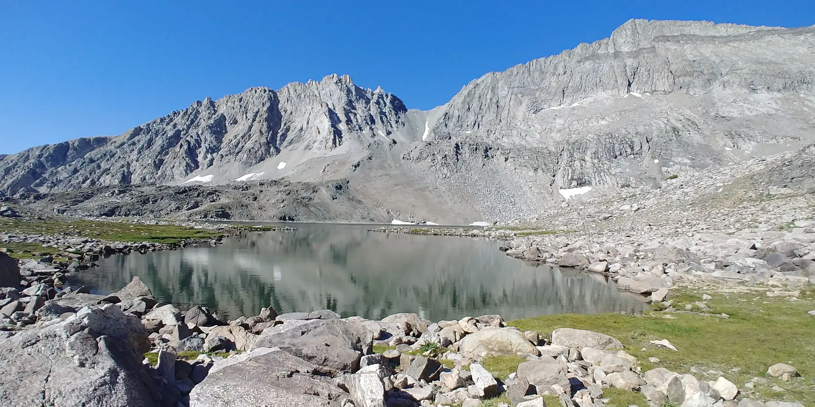 Clear high-country pond reflecting a granite ridgeline in Utah's Wasatch back
