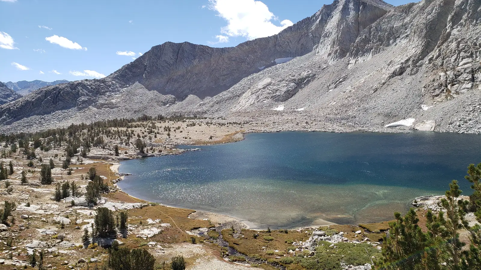 Alpine pond ringed by conifers below granite peaks in Utah's high country